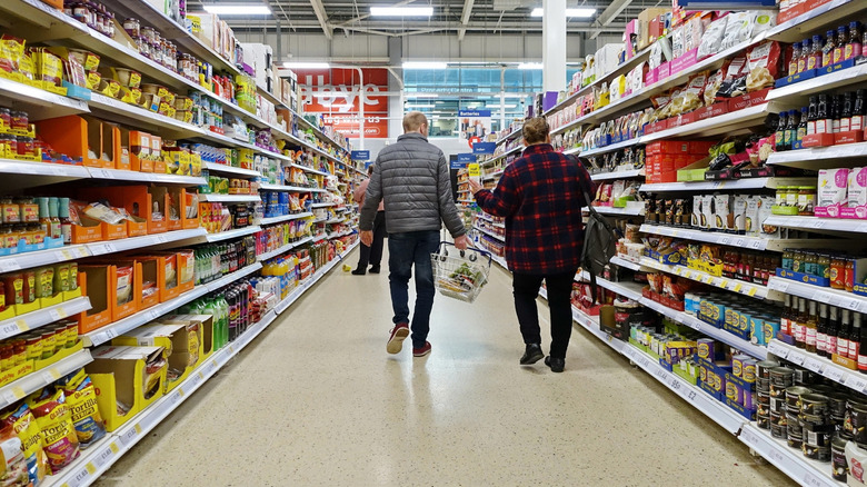 A grocery aisle in a large supermarket with people shopping