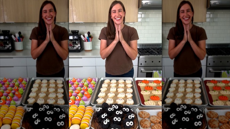 Chelsweets posing in front of counter full of various Halloween themed cookies