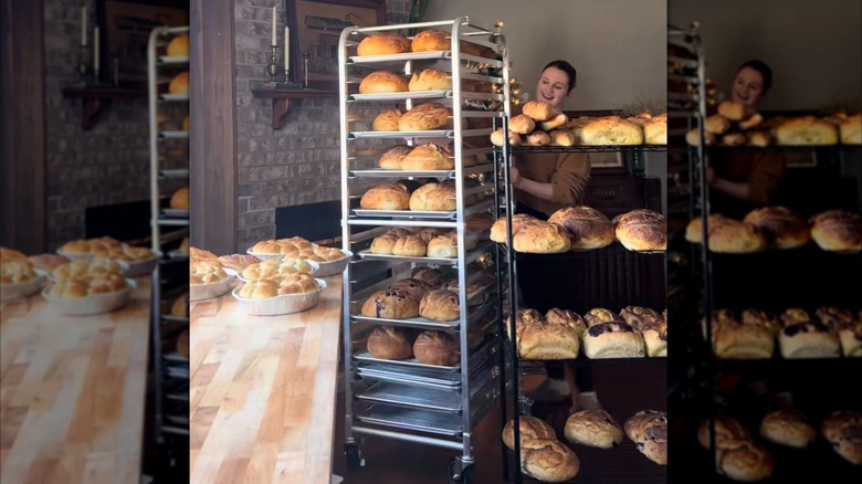 woman bringing a cart of sourdough loaves out with other loaves on display