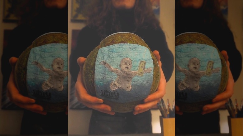 person holding up a loaf of bread with art from Nirvana's album painted onto it