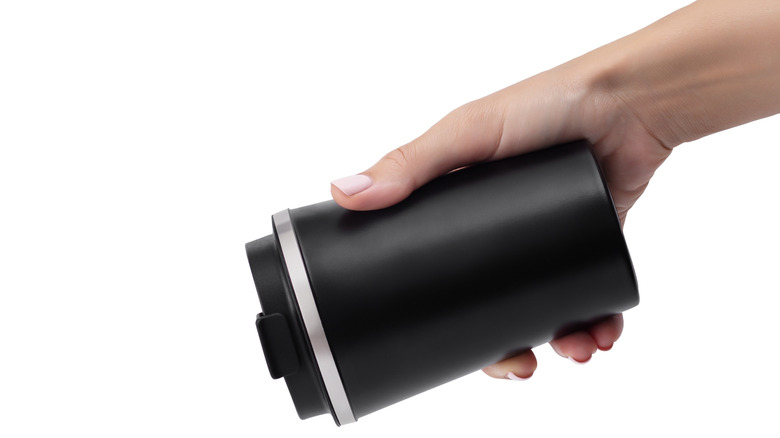 A hand holding coffee cup at an inverted angle