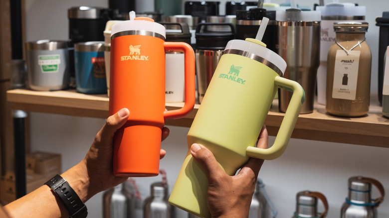 A person comparing two Stanley mugs in a store