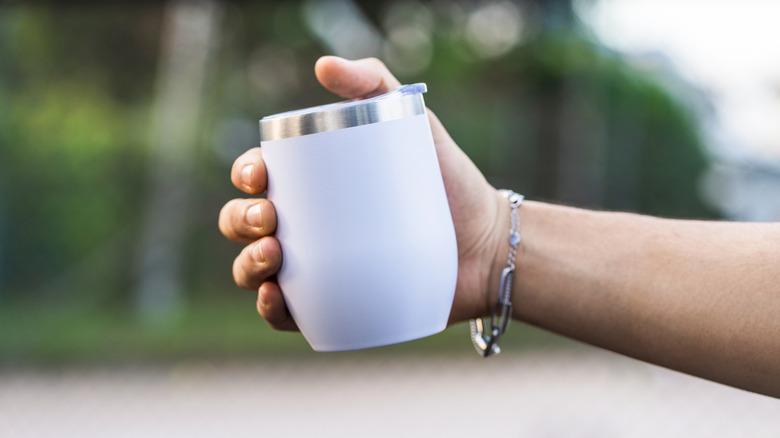 A hand holding a white wine tumbler