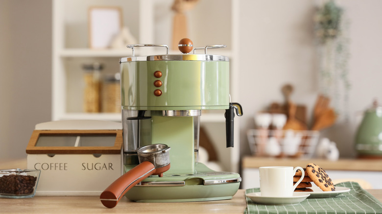 Stylish coffee machine, cups and cookies in modern kitchen
