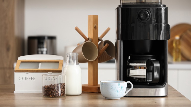 Coffee machine, milk, coffee beans and mug display on wooden countertopw