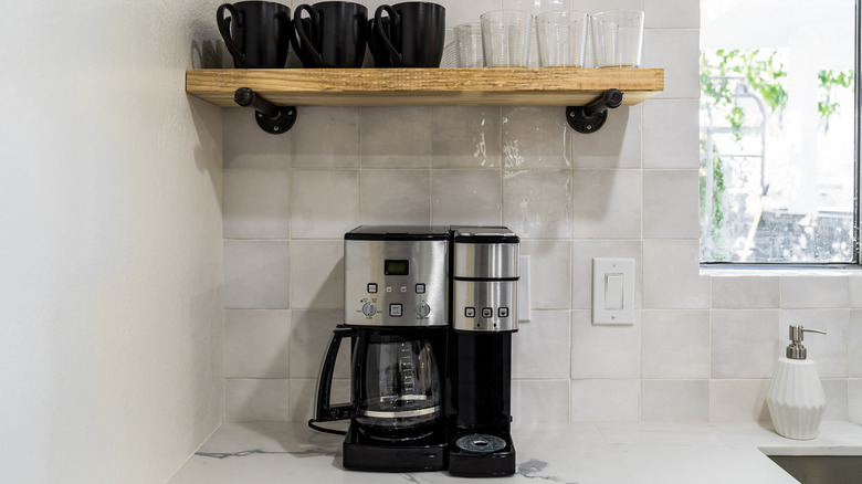 A collection of kitchen appliances including an oven, toaster, coffee machine and mixer placed under a cabinet on a white countertop