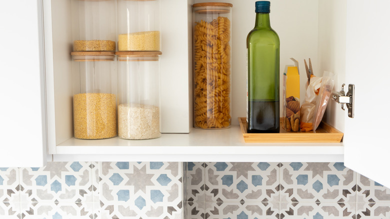 Open pantry cabinet with patterned wallpaper below