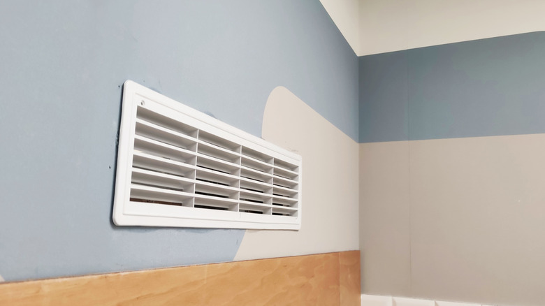 White ventilation grille mounted on a colorful wall