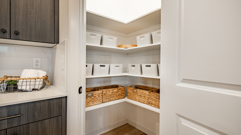 Open pantry doors showing white shelves and wicker baskets within