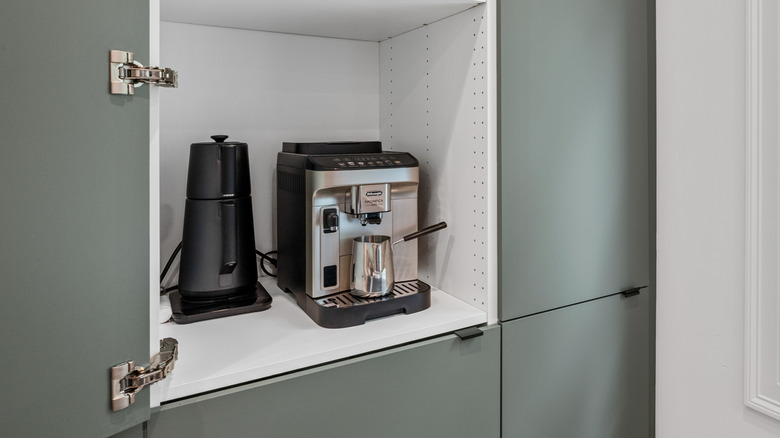 Coffee maker and appliances kept within kitchen cabinet