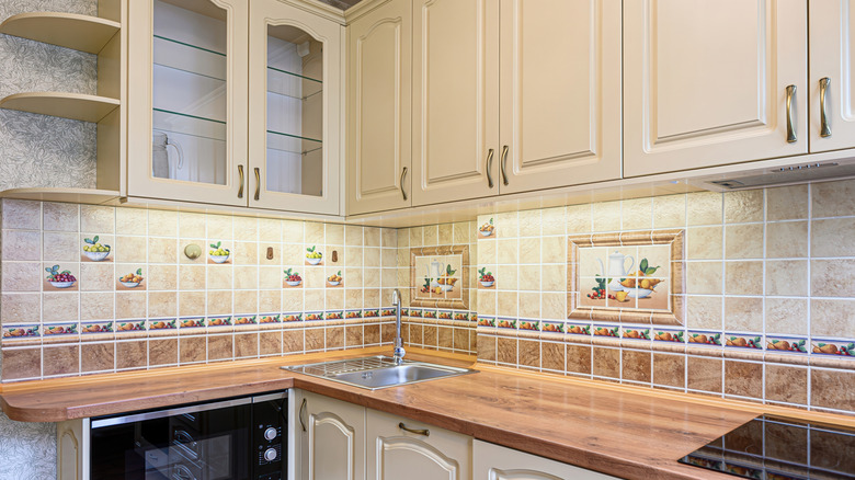 Well-lit kitchen featuring cream-colored cabinets and decorative tiled backsplash