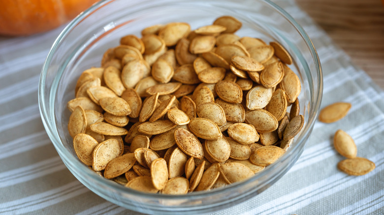 Bowl of roasted pumpkin seeds on grey linen
