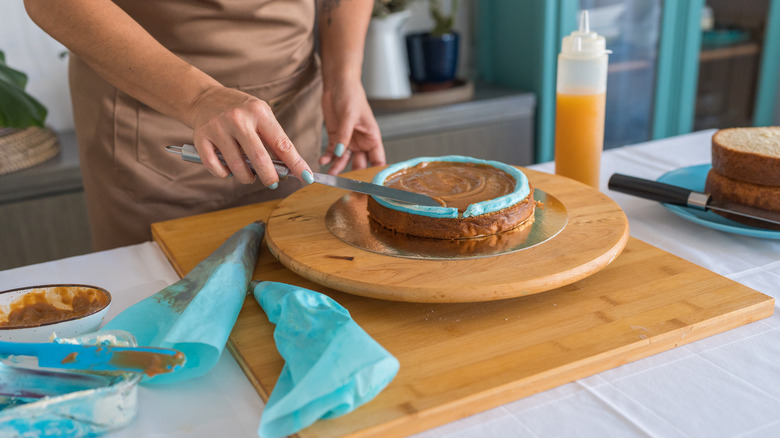 Woman spreading blue whipped cream on a cake