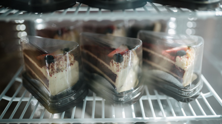 Slices of cake placed in plastic containers inside a refrigerator