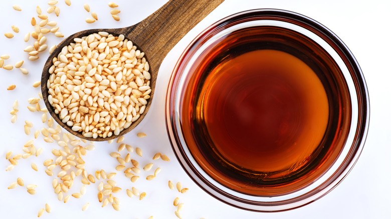 Bowl of sesame oil next to sesame seeds