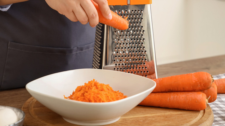 Woman grating carrots into a bowl