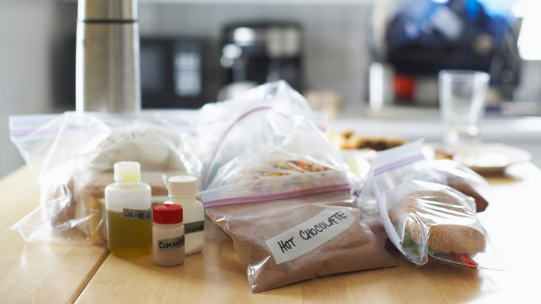 A pile of small, labeled bags and tiny spice containers on a table in the kitchen