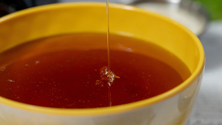 Honey dripping into yellow bowl