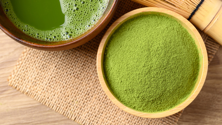 Matcha green tea plus powder in wooden bowls on burlap