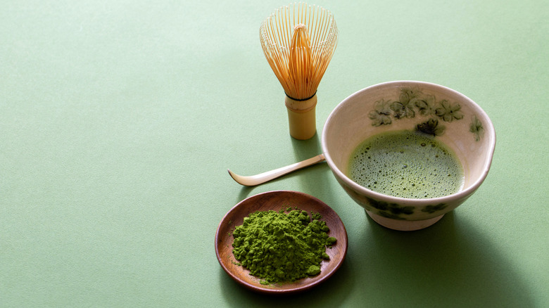 Matcha whisk, matcha slurry, and matcha powder on green table