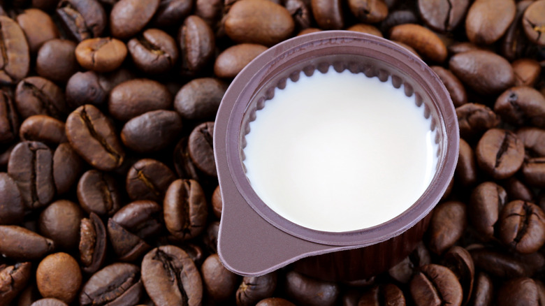 Coffee creamer in small brown bowl surrounded by coffee beans