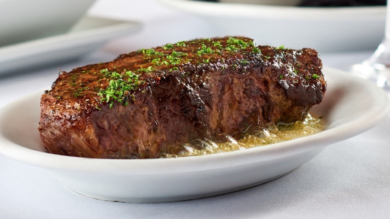 Steak on white plate with bubbling butter at Ruth's Chris