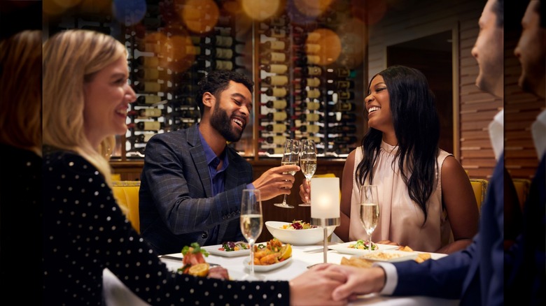 Two couples sitting at white table with champagne and food at Ruth's Chris Steak House