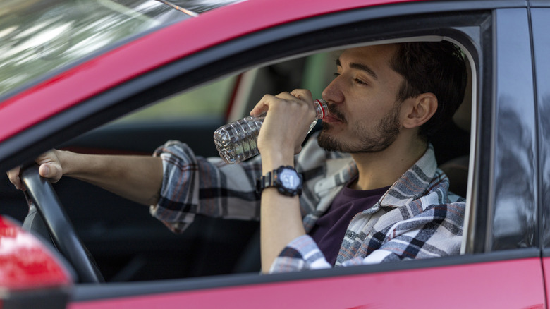 Man drinking a bottle of water in his car