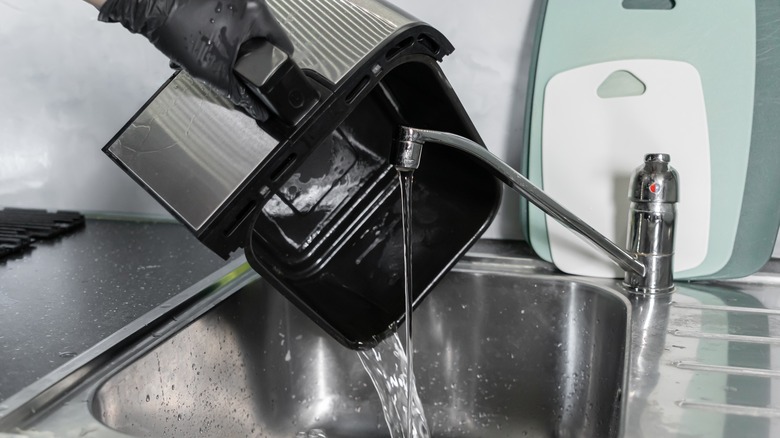 Person washing air fryer part in sink