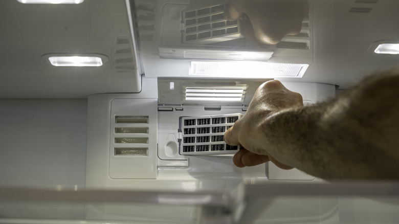Person replacing filter on kitchen appliances