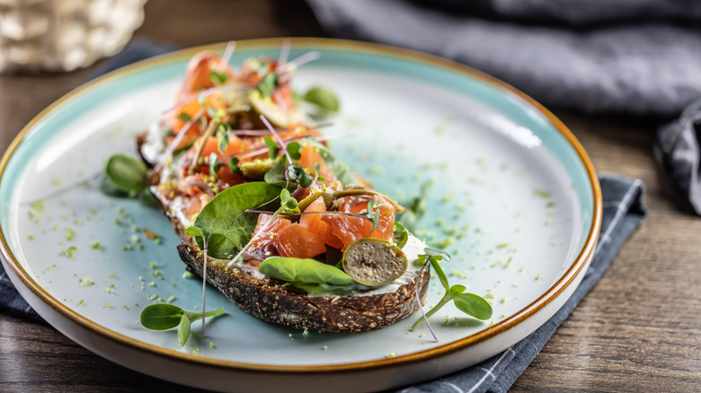 An elegant plate of smoked salmon toast with various greens