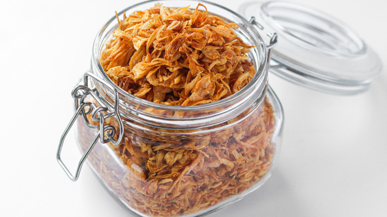 An open glass jar of fried shallots
