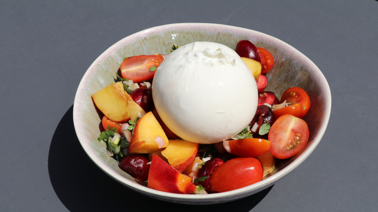 A bowl of burrata salad with some nectarines and cherries