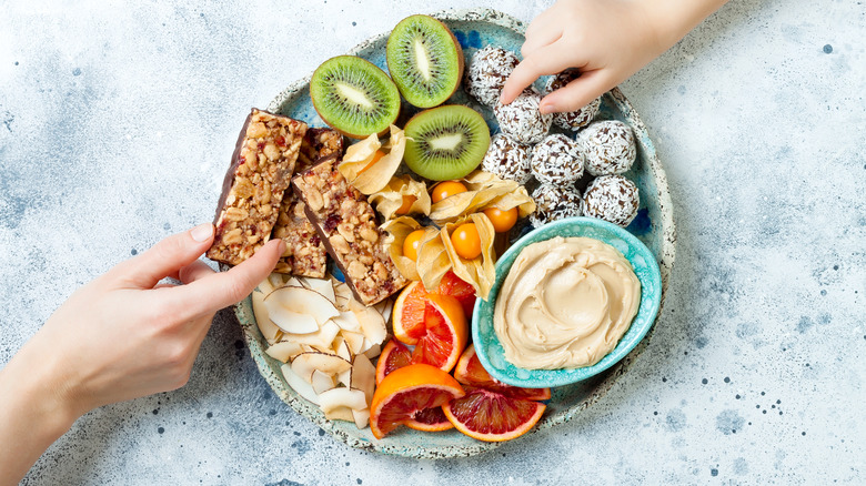 Hands reaching toward colorful snack plate