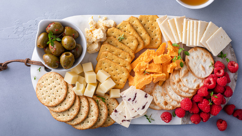 Snack plate with cheese, crackers, fruit, and olives