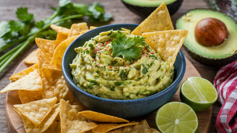 Chips and guacamole on wooden cutting board