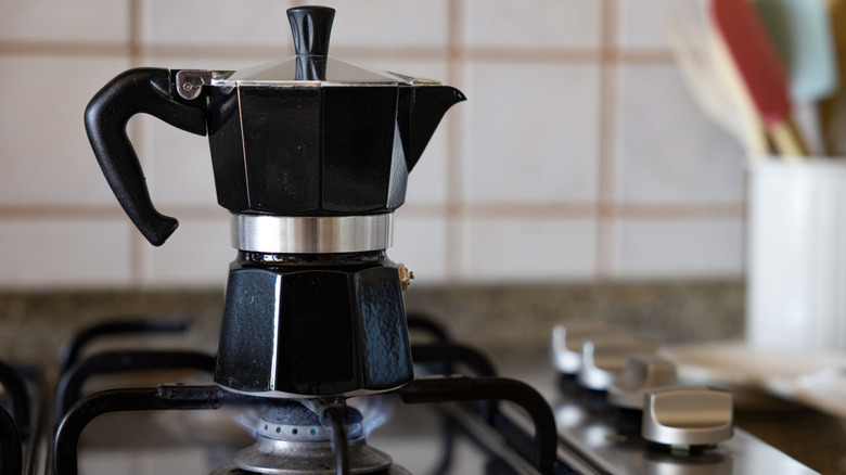 Black Moka pot over low gas flame