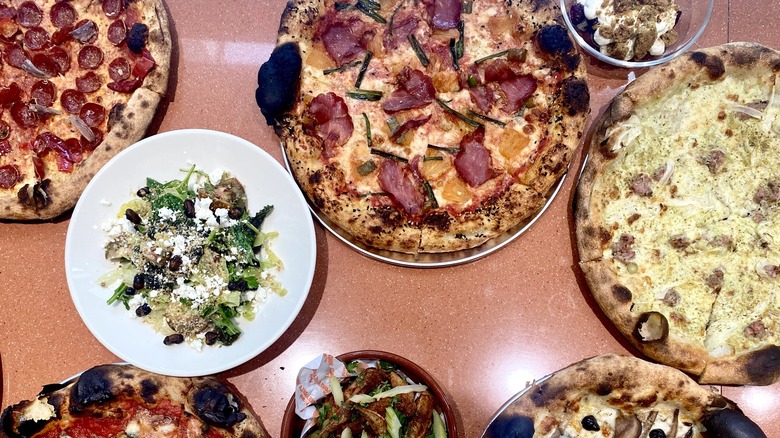 Assortment of pizzas and salads on table