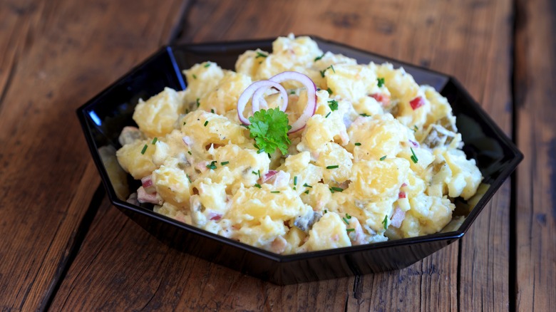 Black bowl filled with German potato salad on a wooden surface