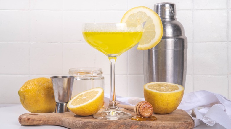 Bee's knees cocktail on cutting board with lemons