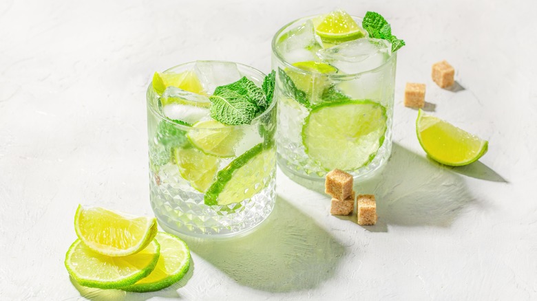 Two mojitos with lime slices on white background