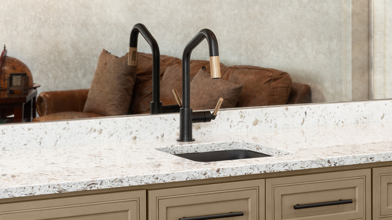 Prep sink placed with a black faucet placed against a mirrored wall
