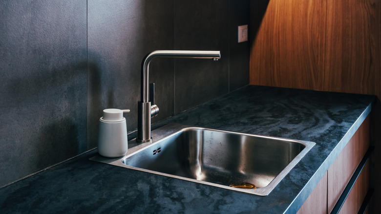Water faucet and topmount sink in sleek dark and wood kitchen