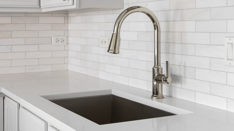 Kitchen sink detail shot with white subway tile backsplash