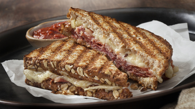 Sliced ham and cheese panini on plate with white parchment paper