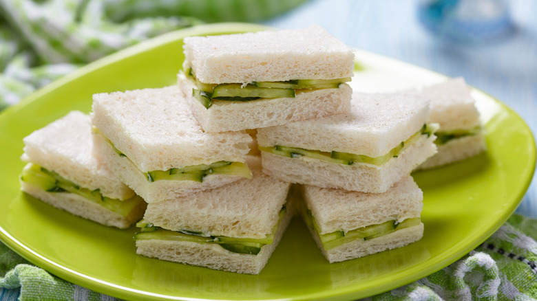 Pile of cucumber tea sandwiches on a green plate