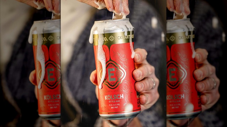 A hand opening a can of Eckhart Kolsch