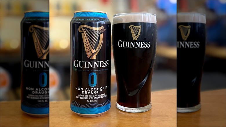 A pint glass of Guinness 0 next to its can