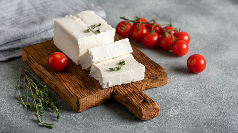 Feta on cutting board with tomatoes and thyme