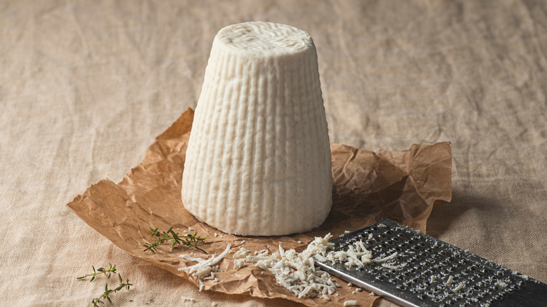 Mound of ricotta on brown paper with grater